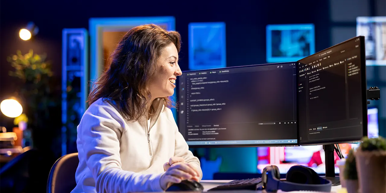 Desenvolvedora escrevendo código em dois monitores