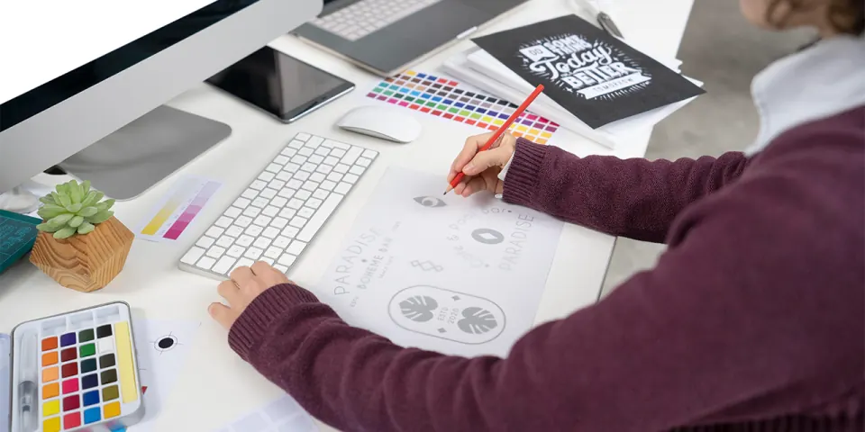Designer desenhando variações de uma marca ao lado de cartelas de cor